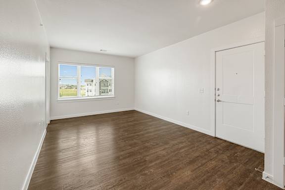 Empty room with wooden floor and white walls.