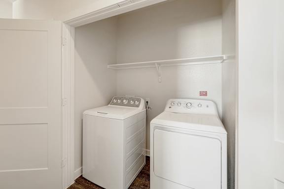 Two white front loading washing machines in a laundry room.