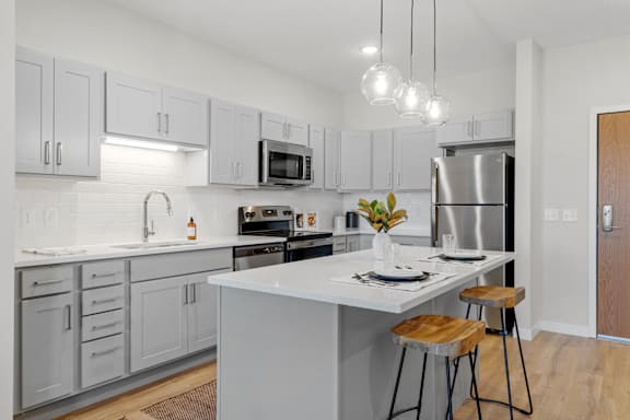 A kitchen with a white island and grey cabinets.