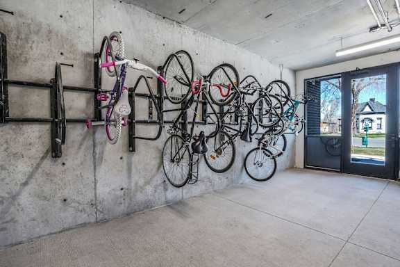 A wall of bicycles is mounted on a concrete wall.