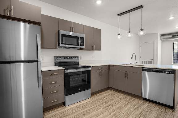 A modern kitchen with stainless steel appliances and wooden flooring.