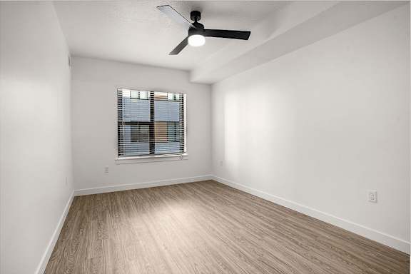 A room with a ceiling fan and a window with blinds.