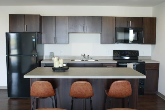 a kitchen with a large island with four chairs around it