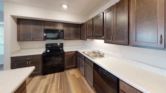 a kitchen with dark wood cabinets and white countertops