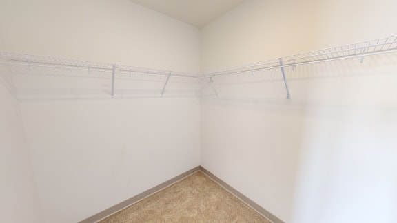 a walk in closet with white walls and beige carpet