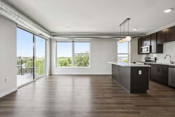 an open kitchen and living room with a large window and a balcony