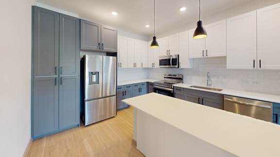 A modern kitchen with a stainless steel refrigerator and a white countertop.