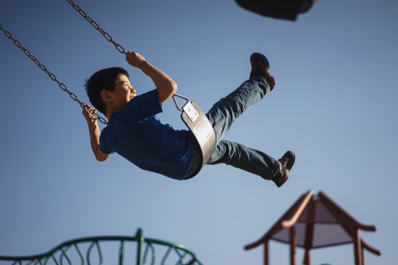a young boy swinging on a swing on a playground