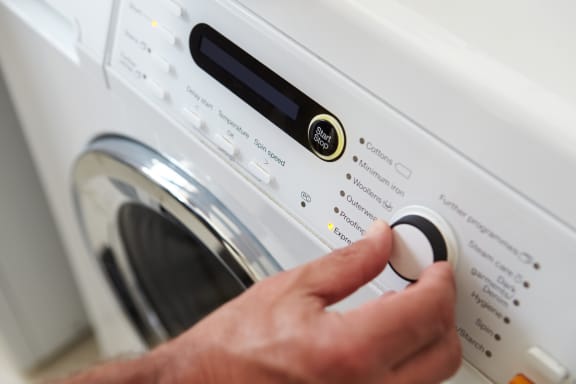 a hand adjusting the settings on a washing machine