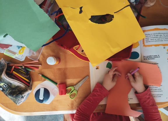 a child cutting out paper with scissors and glue on a table