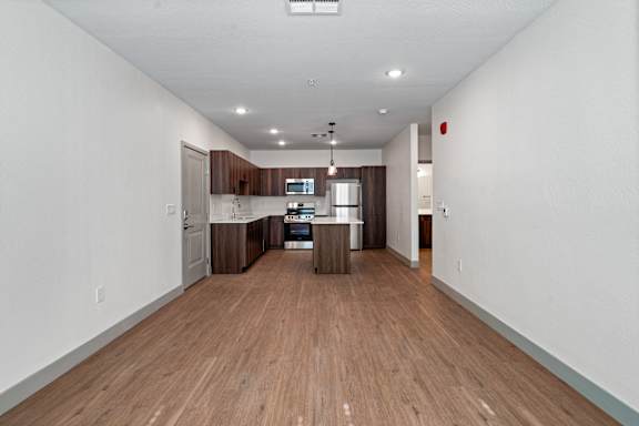 A long, empty hallway with wood floors and white walls.