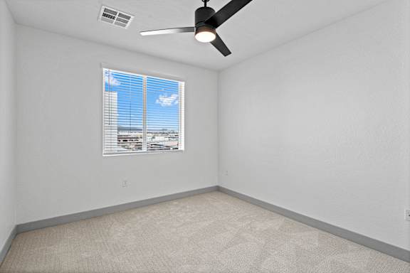 A room with a ceiling fan and a window with blinds.