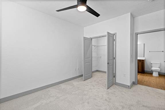 A room with a ceiling fan and a toilet in the corner.