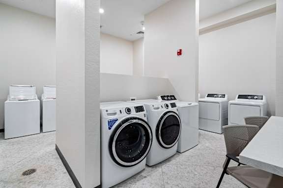 A laundry room with washing machines and a table.