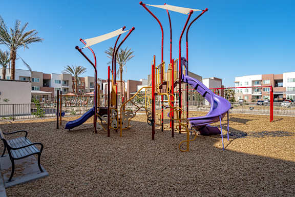 A playground with a purple slide and a red and yellow structure.