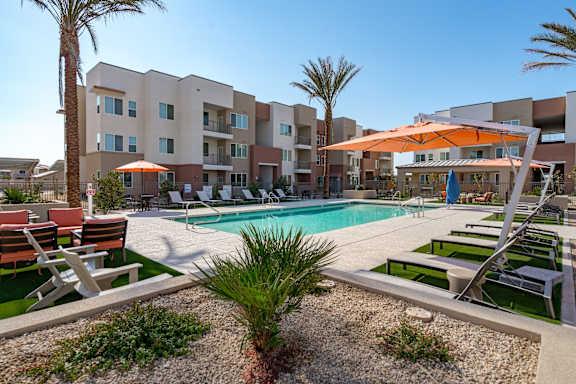 A pool area with a sunshade and a building in the background.