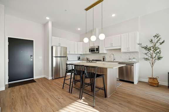 A modern kitchen with a bar stool and a tree.