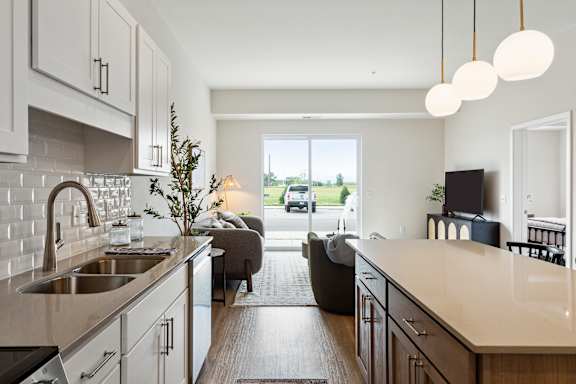 A modern kitchen with a large island and a view of the street outside.