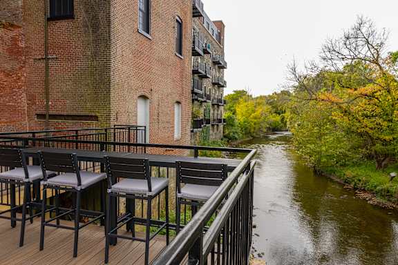 Two chairs are on a balcony overlooking a river.