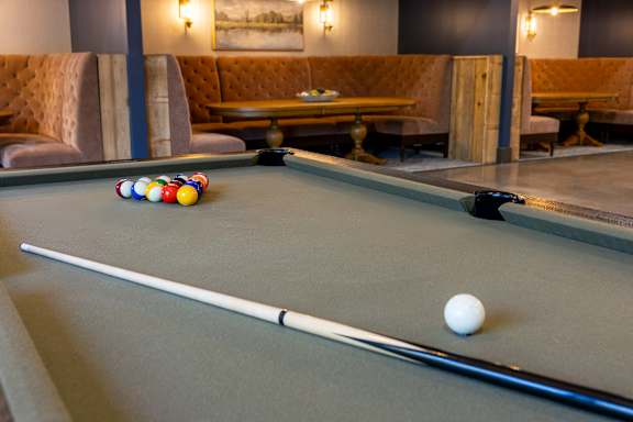 A pool table with a white ball and a cue stick.