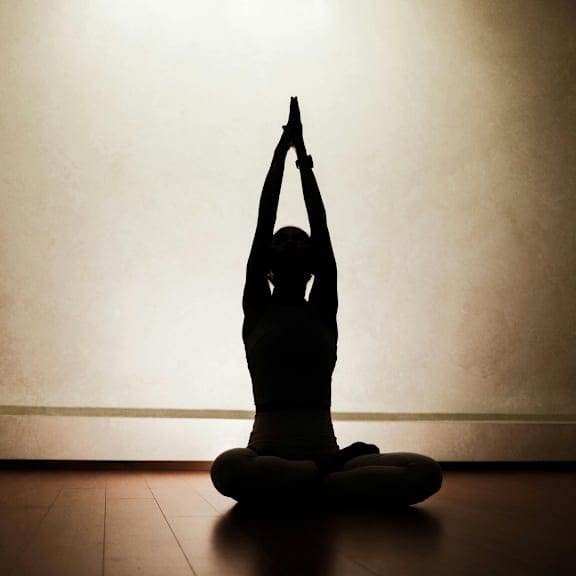 A person is sitting cross-legged on the floor in a meditative pose. at The Dean at Creekview Apartments, Delaware, 19711