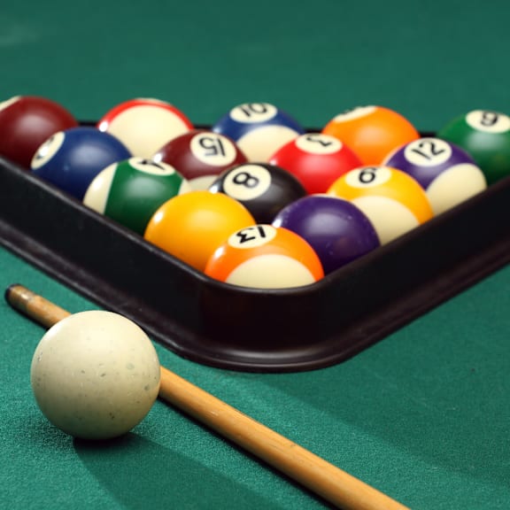 A pool table with a white ball and a cue stick. at The Dean at Creekview Apartments, Newark, 19711