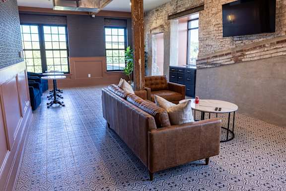 A living room with a brown couch and a television mounted on the wall.