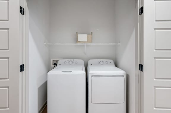 Two white washing machines in a small laundry room.