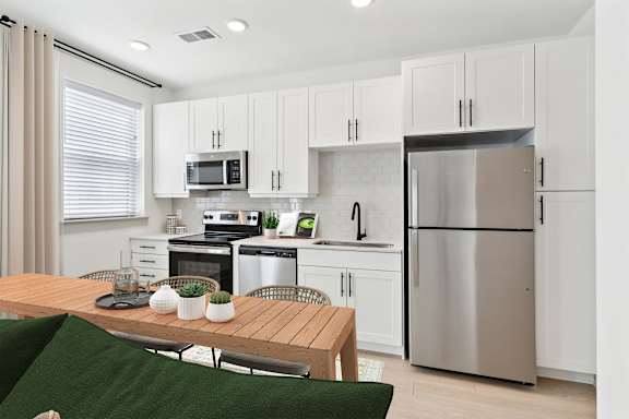 A modern kitchen with a wooden table and stainless steel appliances.