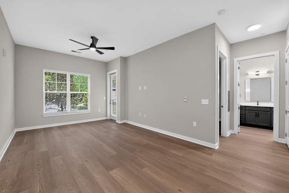 A room with a ceiling fan and wooden flooring.