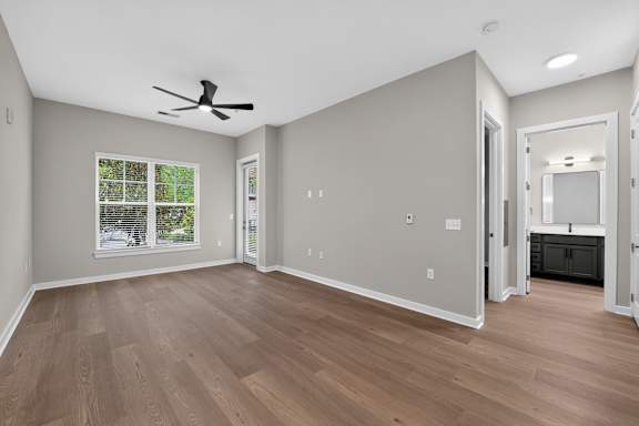 A room with a ceiling fan and wooden flooring.