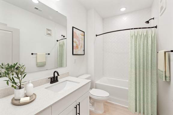 A white bathroom with a green shower curtain.