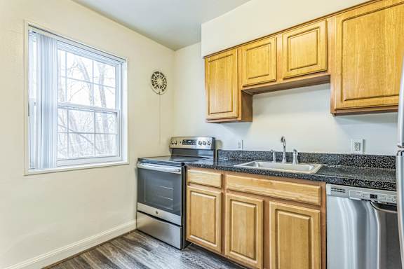 A kitchen with wooden cabinets and a black granite countertop at The Fields of Silver Spring, Maryland, 20902