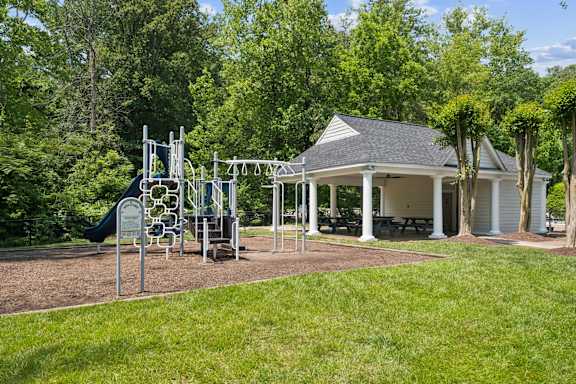 A playground with a swing set and a gazebo in the background.