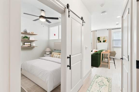 A bedroom with a white bed and a ceiling fan.