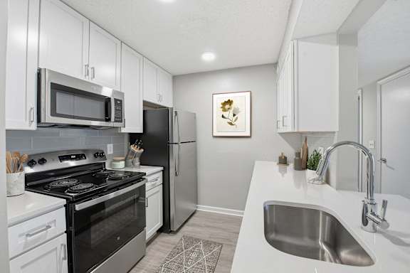 A modern kitchen with white cabinets and stainless steel appliances at Brampton Moors, Cary, NC