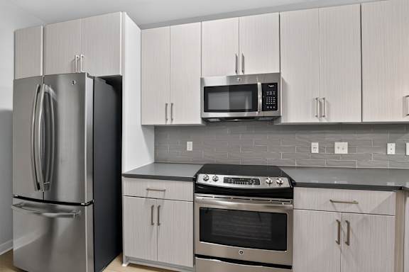 A kitchen with a refrigerator, oven, and microwave.