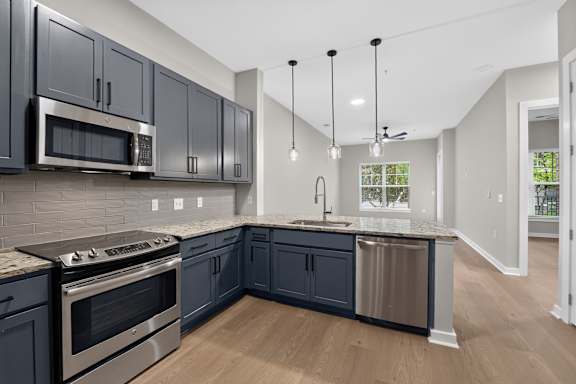 A kitchen with dark cabinets and a stainless steel dishwasher.