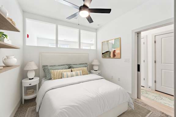 A bedroom with a large bed and a ceiling fan.