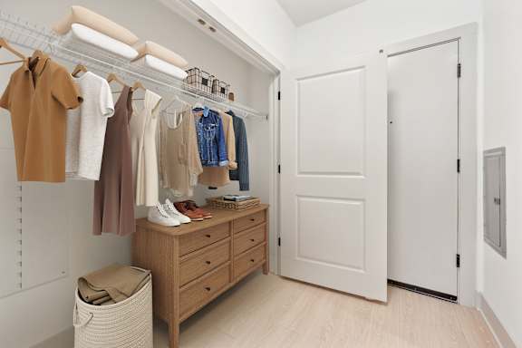 A white closet with clothes hanging and a white door.