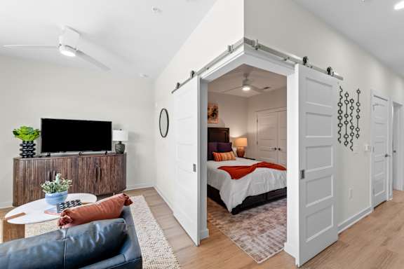A bedroom with a bed, a couch, and a television at Hawkins Press Apartments, Charlotte, 28203