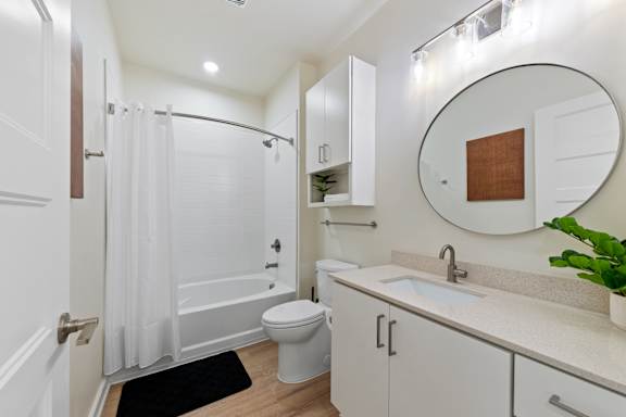 A white bathroom with a toilet, sink, and shower at Hawkins Press Apartments, Charlotte, NC