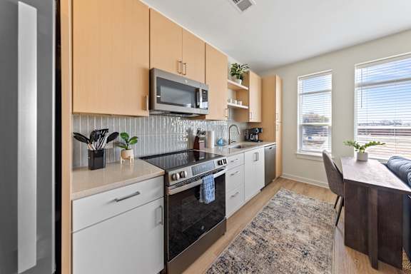 A kitchen with white appliances and wooden cabinets at Hawkins Press Apartments, Charlotte, 28203