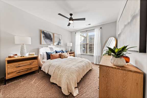 A bedroom with a bed, dresser, and ceiling fan.