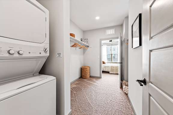 A white washing machine is in a narrow hallway.