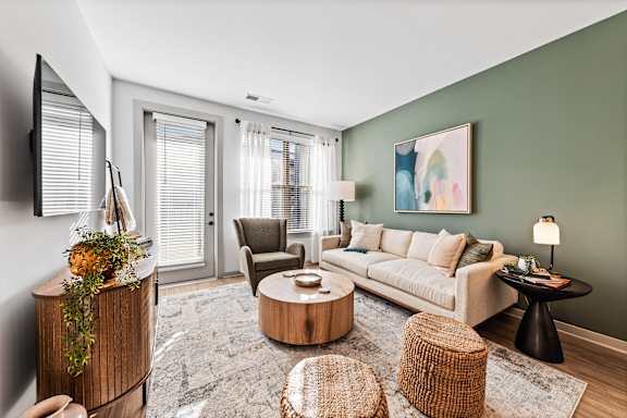 A living room with a white sofa, a wooden coffee table, and a TV on the wall.