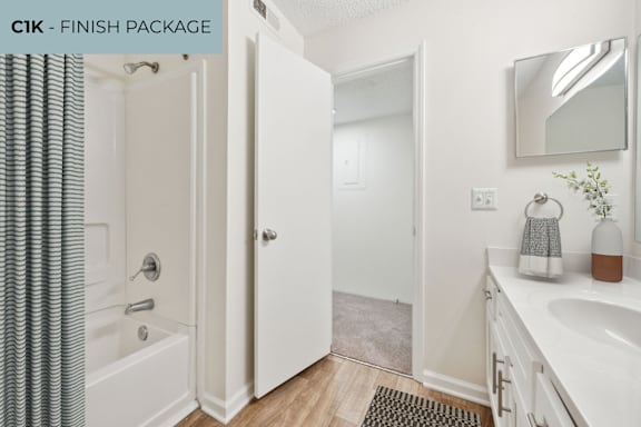 A bathroom with a white tub, sink, and shower curtain.