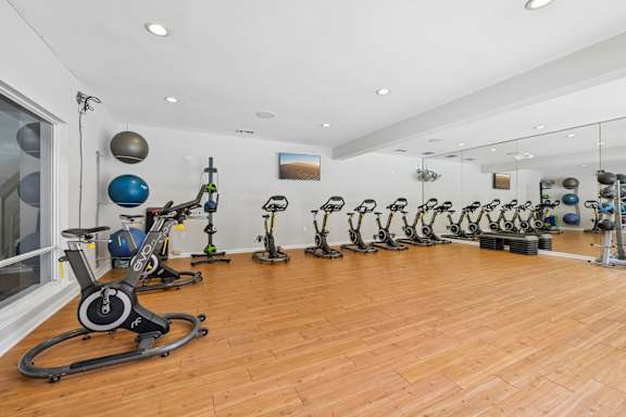 A gym with a row of stationary bikes and a mirror on the wall.