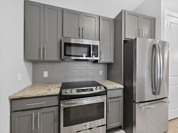 A kitchen with a stove, oven, microwave, and refrigerator.