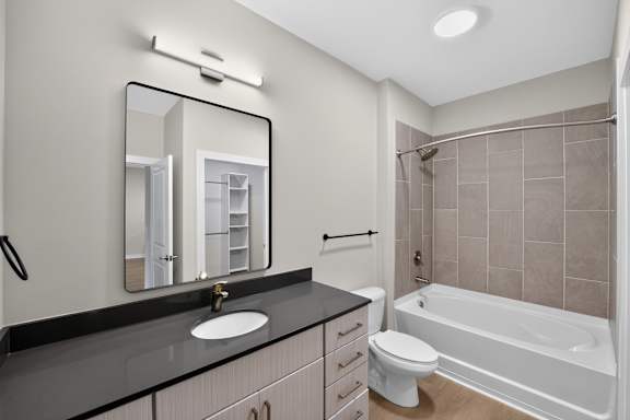 A bathroom with a sink, mirror, toilet and bathtub.
